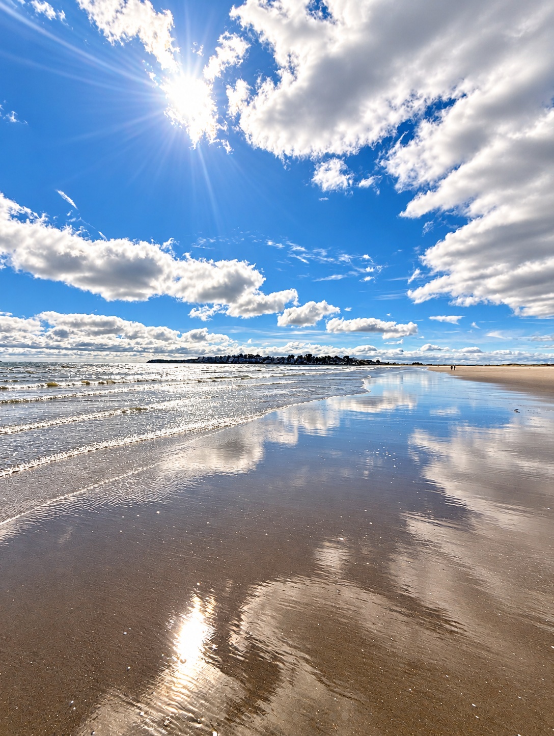 Nahant Beach beneath bright clouds, reflected in the wet sand