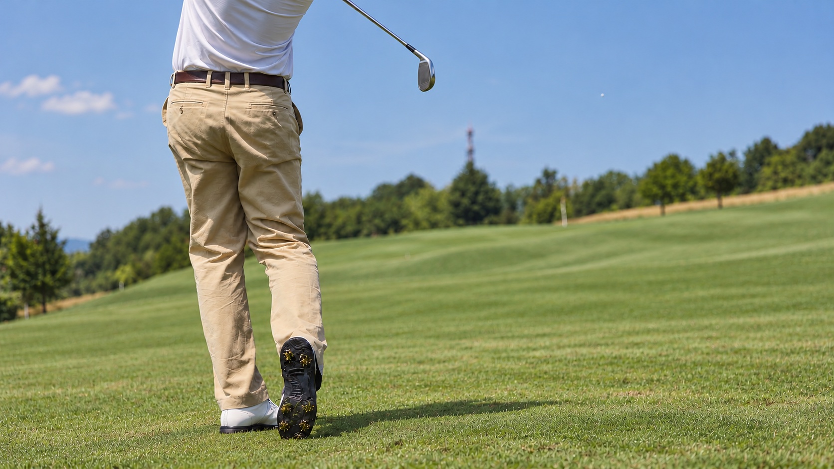 A golfer completing a swing on a green course