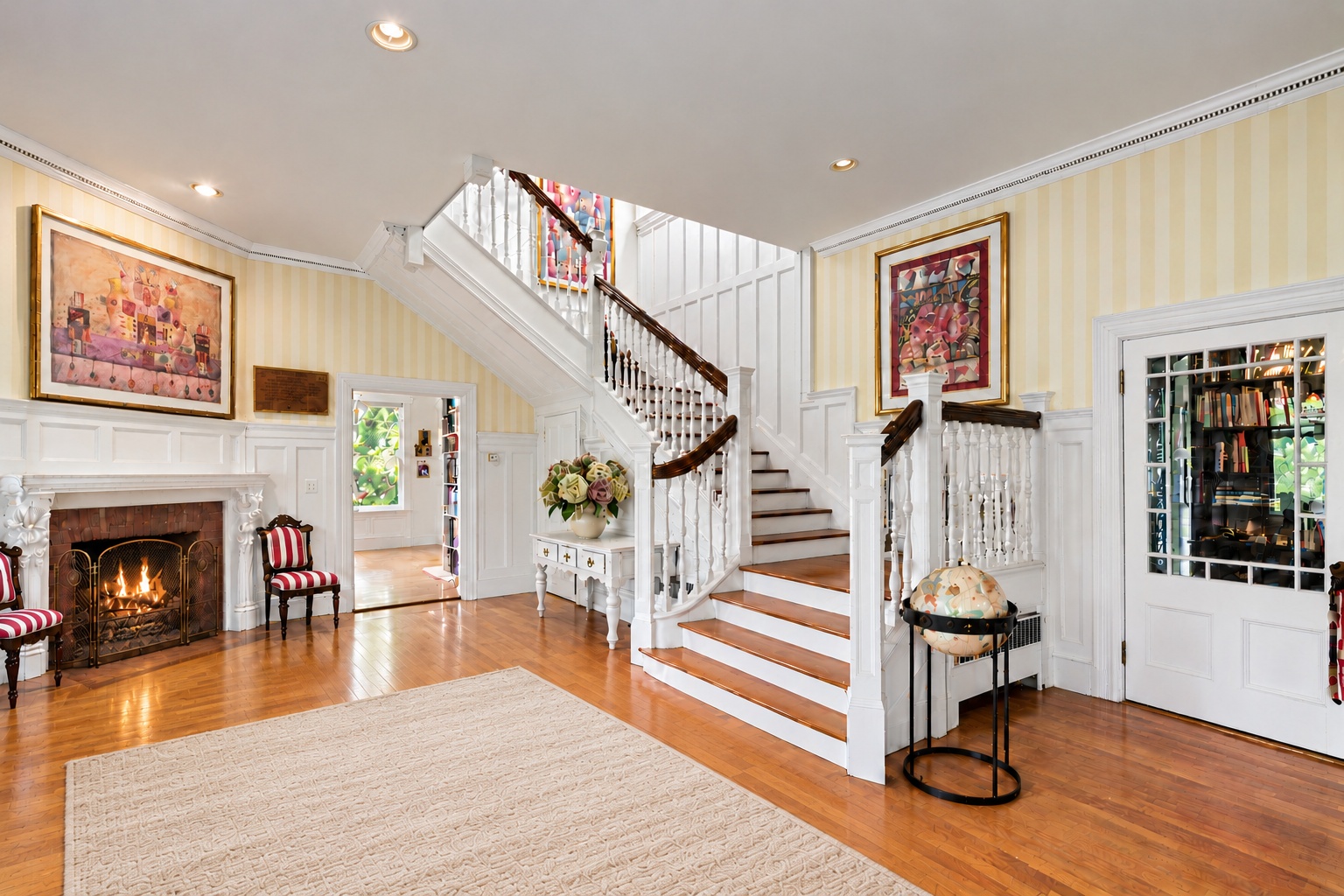 Entry hall with a broad staircase, fireplace, artwork, and sisal rug