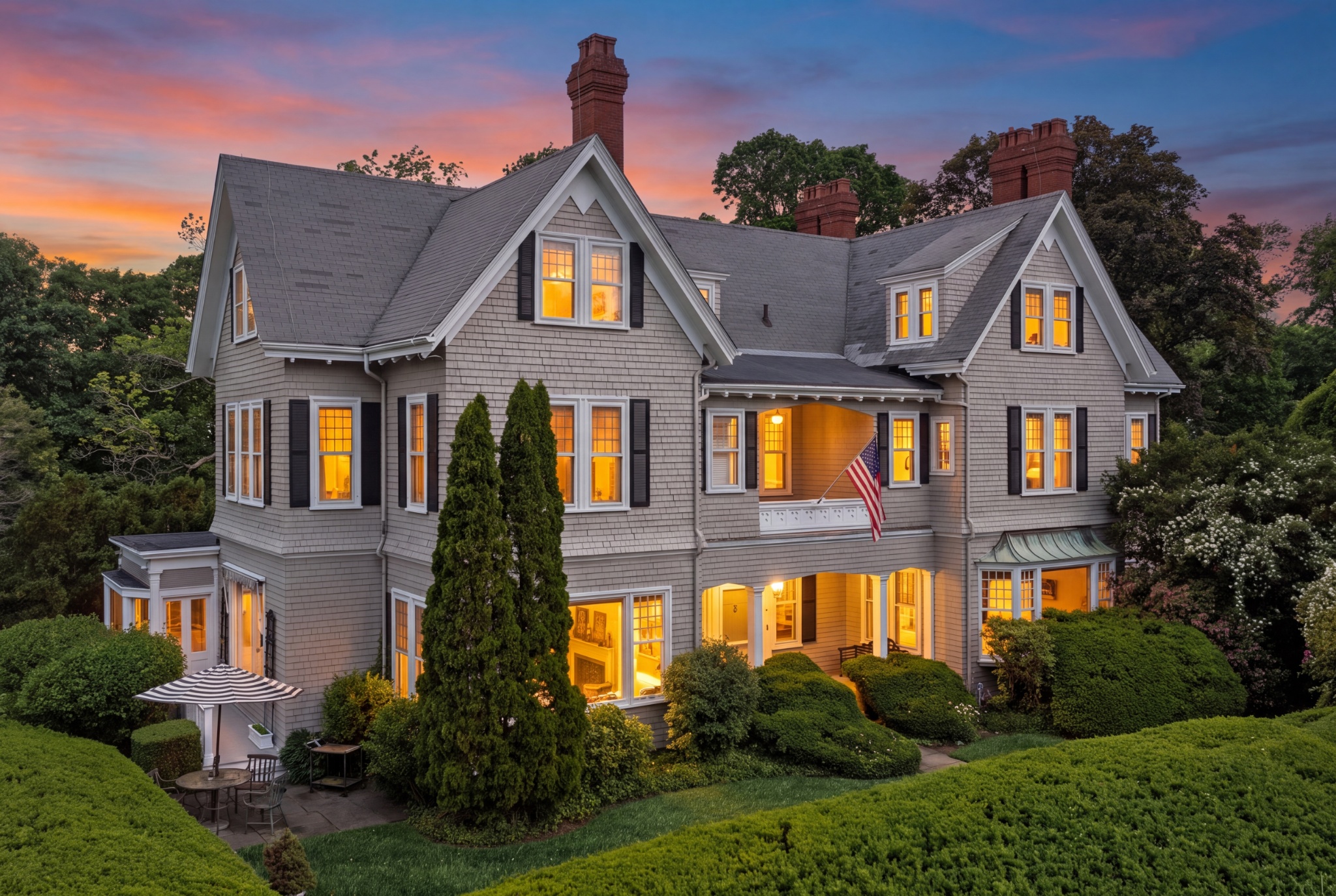51 Cliff Street at twilight, with its Queen Anne roofline, illuminated windows, porch, and gardens