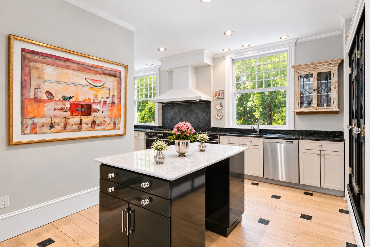 Light kitchen with an island, flowers, artwork, and timber floors