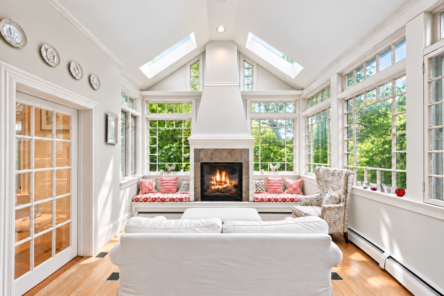 Sunlit sitting room with a fireplace, window seats, and a white sofa