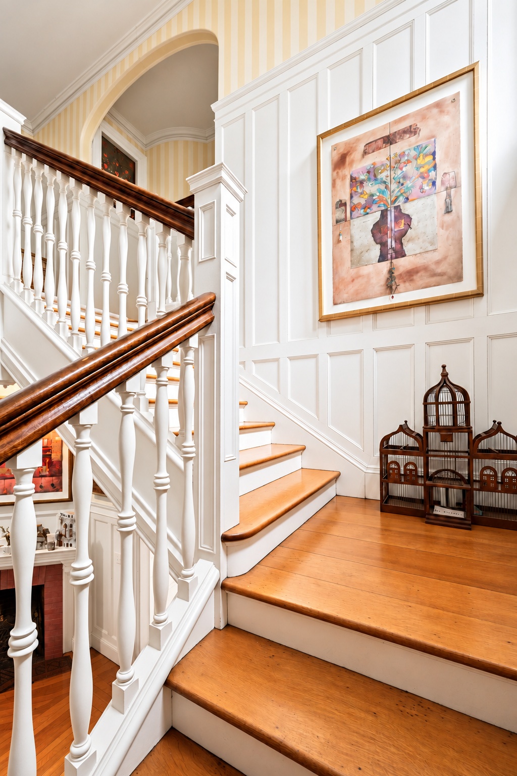 Carved timber staircase with white balusters and artwork
